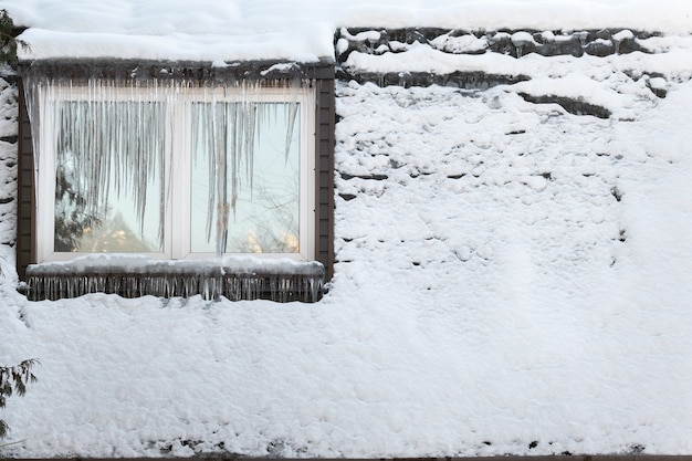 Foto pingentes de gelo na janela da casa em um dia gelado.