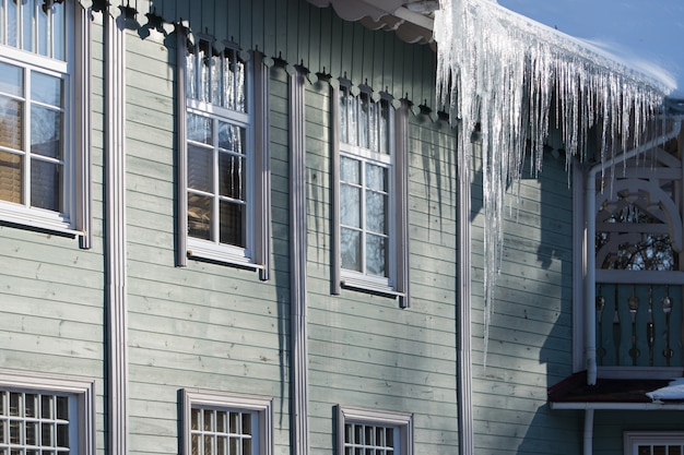 Pingentes pendurados no telhado de um edifício de madeira no inverno em tempo ensolarado