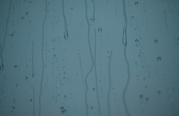 Pingos de chuva escorrem pelo vidro contra o céu noturno. pingos de chuva na janela.