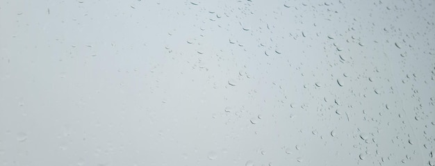 Pingos de chuva na janela contra o céu cinza