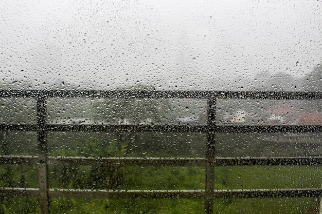 Pingos de chuva na vidraça com névoa branca no fundo do corrimão da varanda