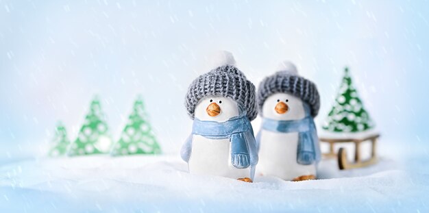 Pinguine mit Hüten, die einen Weihnachtsbaum auf einem Schlitten aus dem Wald tragen