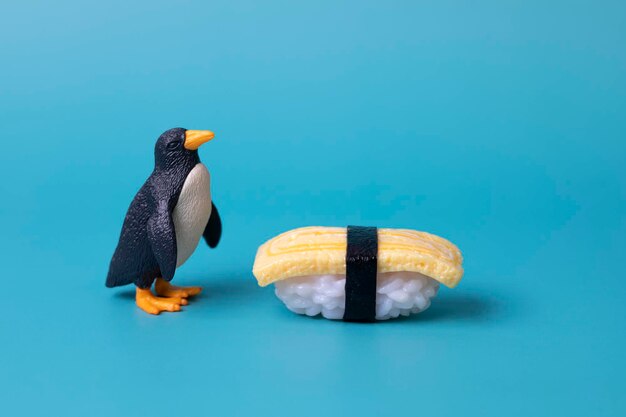 Foto un pingüino se para al lado de un rollo de sushi.