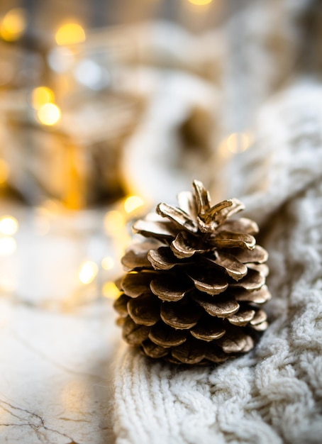 Pinha pintada de ouro no cobertor de malha no fundo da decoração do feriado de natal