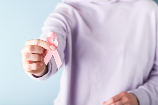 Pink Breast Cancer Awareness Ribbon Weibliche Hände, die rosa Schleife auf blauem Hintergrund halten Brustkrebsbewusstsein und Oktober Rosa Tag Weltkrebstag Draufsicht Mock up