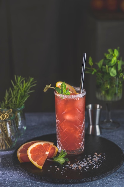 Pink Grapefruit Mezcal Paloma Cocktail en vaso alto con gotas de agua sobre la mesa en casa real Nuevo concepto de vida de cuarentena Cerrar profundidad superficial del campo