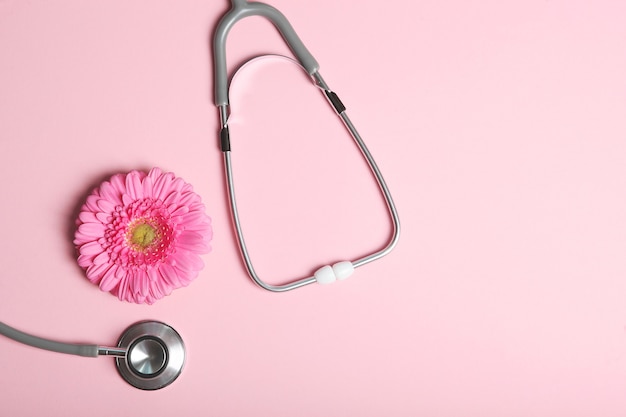 Pink Ribbon Gerbera und Stethoskop auf einem farbigen Hintergrund Draufsicht