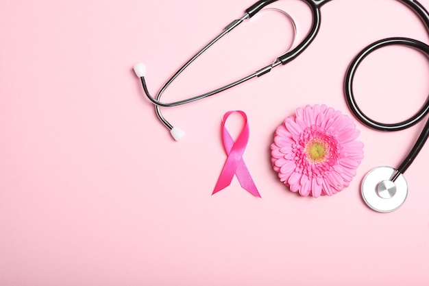 Pink Ribbon Gerbera und Stethoskop auf einem farbigen Hintergrund Draufsicht