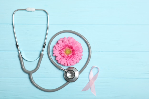 Pink Ribbon Gerbera und Stethoskop auf einem farbigen Hintergrund Draufsicht