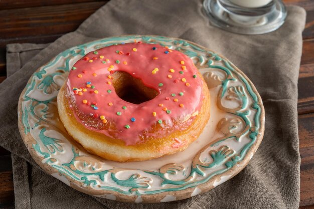 Pinker Donut in schönem Dressing ist auf dem Designerteller Grünes Retromuster Ansehen unter 45