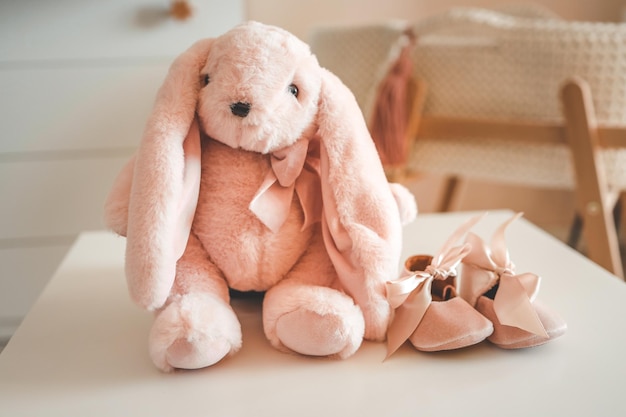 Foto pinkes weiches spielzeug kaninchen und babyschuhe kinderkonzept