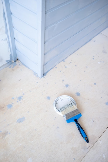 Foto pinsel in grauer farbe liegt auf einer metallabdeckung. streichen einer holzwand. hausrenovierung