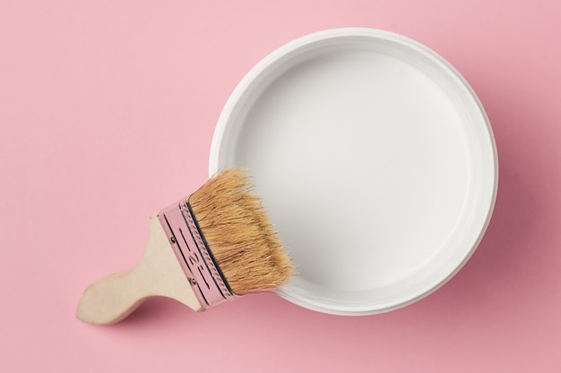 Pinsel und Farbe können mit weißer Farbe auf einem rosa Hintergrund, Draufsicht