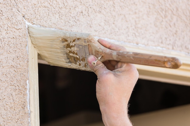 Pintador profesional cortando con pincel para pintar el marco de la puerta de la casa