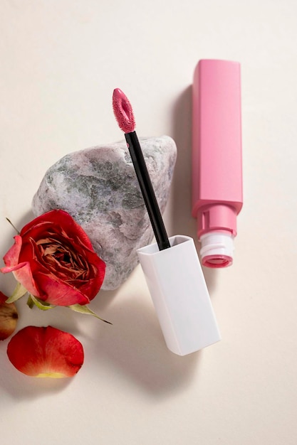 Pintalabios líquido rosa y pincel aplicador con flores y piedra Producto cosmético de maquillaje Fondo brillante