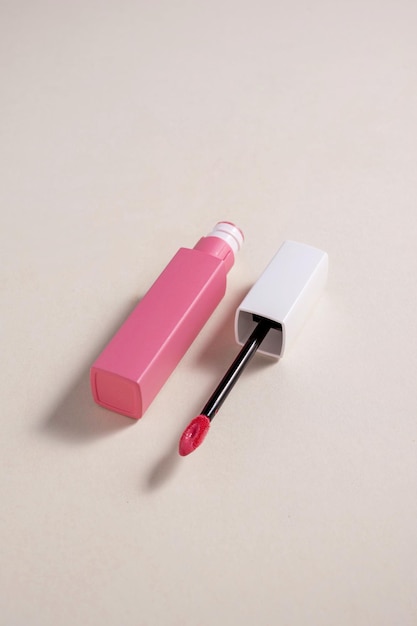 Pintalabios líquido rosa y pincel aplicador con tubo abierto Producto cosmético de maquillaje Fondo neutro cálido