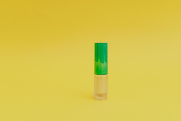 Pintalabios con una tapa verde brillante sobre un fondo amarillo