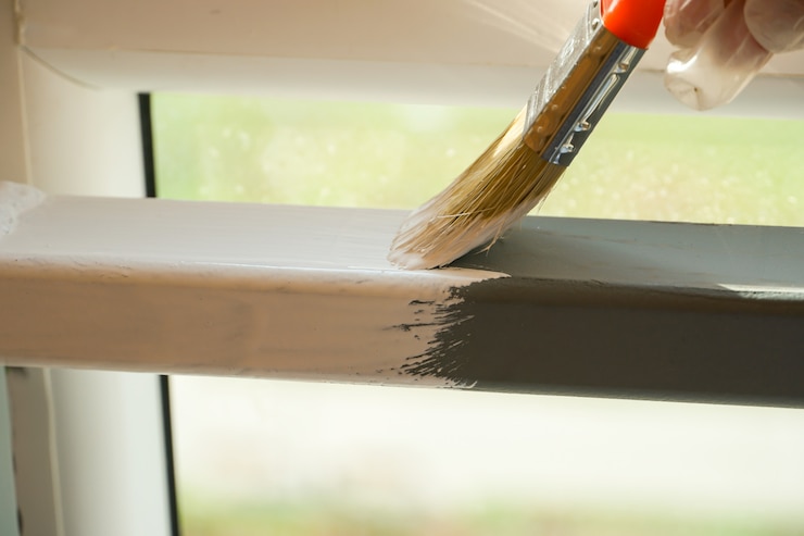 Foto pintando estruturas metálicas com tinta branca usando um pincel