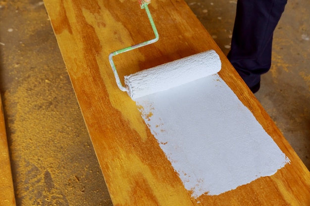 Pintando la madera con rodillo de pintura blanca.