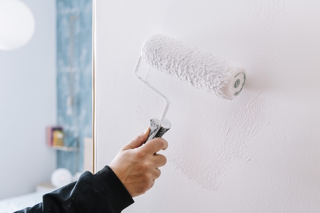 Pintando a mano una pared en blanco con un rodillo