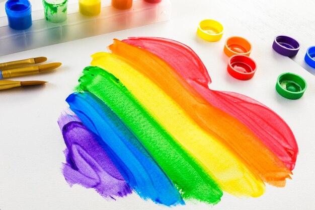 Foto pintando o coração do orgulho gay do arco-íris em um papel branco.