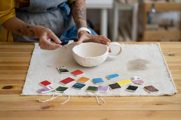 Foto pintar cerámica ceramista prueba diferentes colores para la taza de cerámica durante la clase magistral del taller