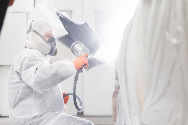 Pintar el coche en la sala de pintura con pistola de pintura blanca