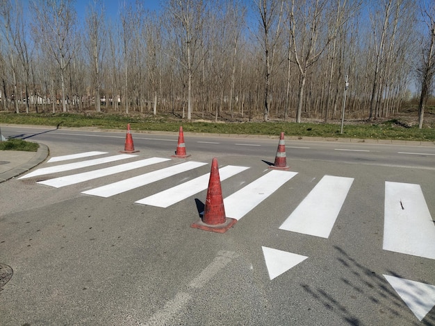 Pintar cruces de peatones con pintura nueva advertencia de carretera cono naranja plástico rayas blancas en el