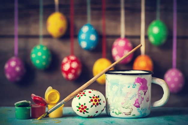 Pintar huevos de Pascua y colgar huevos coloridos sobre fondo de madera rústica