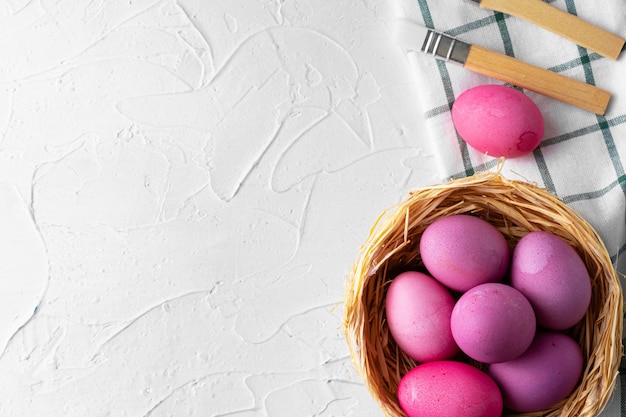 Pintar huevos de Pascua en rosa en la mesa blanca, vista desde arriba