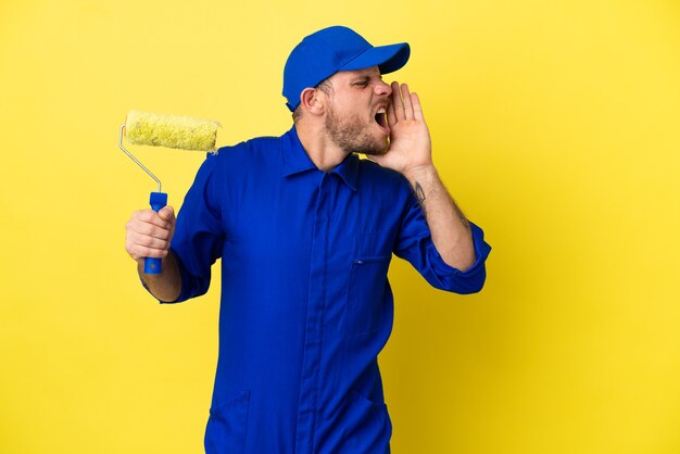 Pintor brasileiro isolado em fundo amarelo gritando com a boca bem aberta para o lado