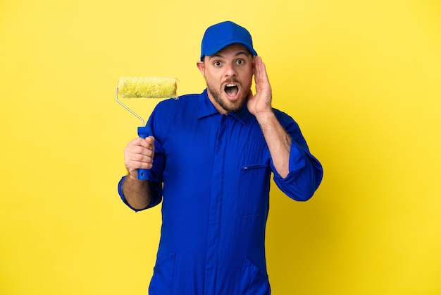 Pintor brasileño aislado sobre fondo amarillo con sorpresa y expresión facial conmocionada