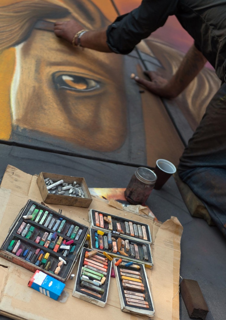 Foto un pintor callejero dibujando con tizas en el suelo.