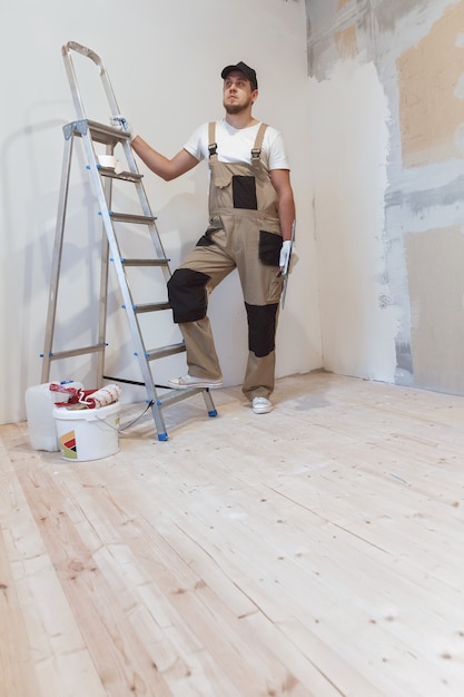 Pintor com uma espátula nas mãos faz reparos em casa. Conceito de renovação de sala.