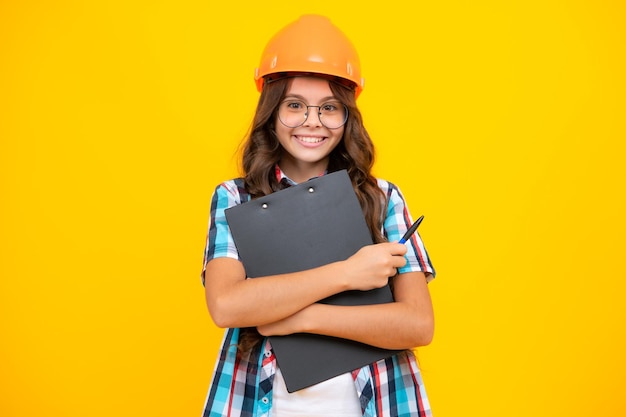 Pintor de criança adolescente no capacete com prancheta Criança no capacete Engenheiro de criança no canteiro de obras Renovação e reparo