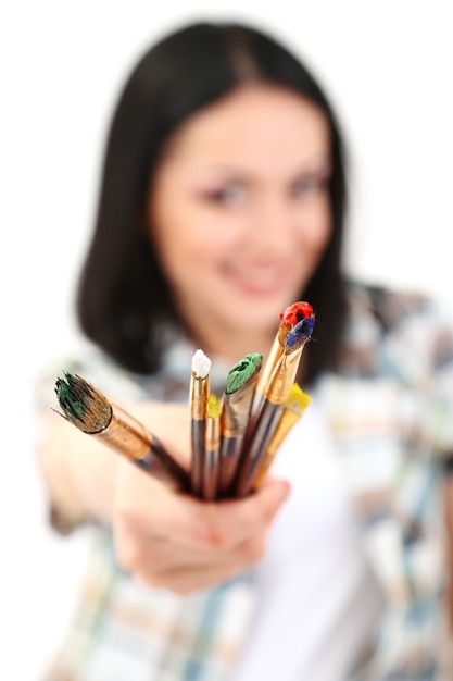 Foto pintor de mulher jovem e bonita com pincéis, isolado na superfície branca