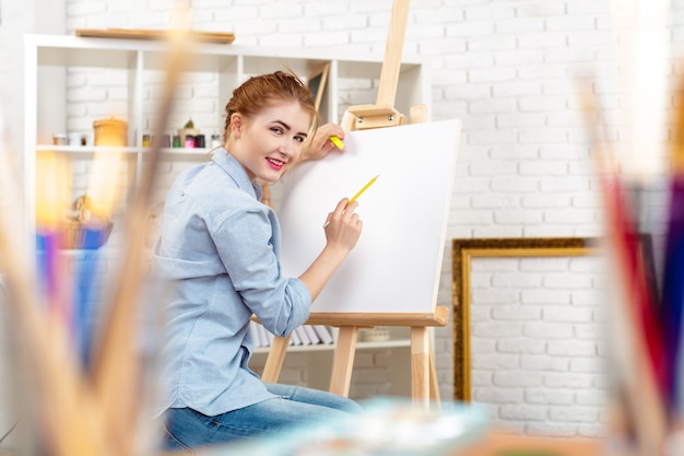 Pintor hermoso de la mujer joven en el trabajo