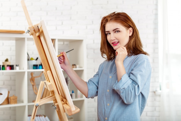 Pintor hermoso de la mujer joven en el trabajo