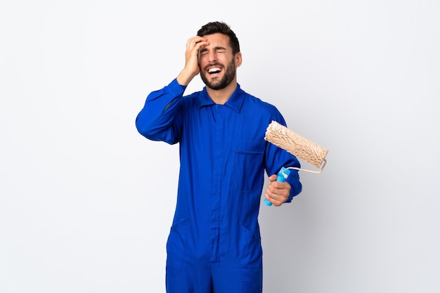 Foto pintor hombre sosteniendo un rodillo de pintura aislado en blanco riendo