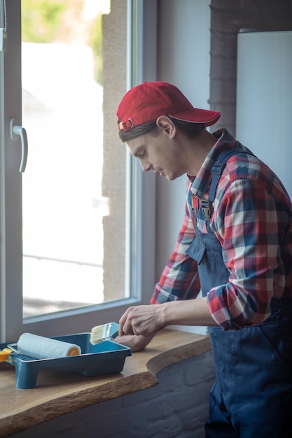 Pintor joven enfocado preparándose para pintar ventanas