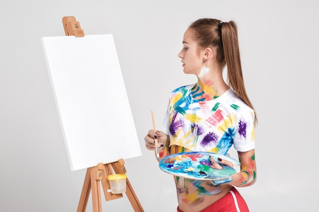 Pintor mujer manchada de pintura colorida dibuja sobre lienzo