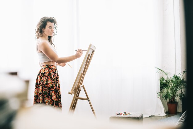 Pintor sorridente sendo ocupado com seu trabalho na oficina