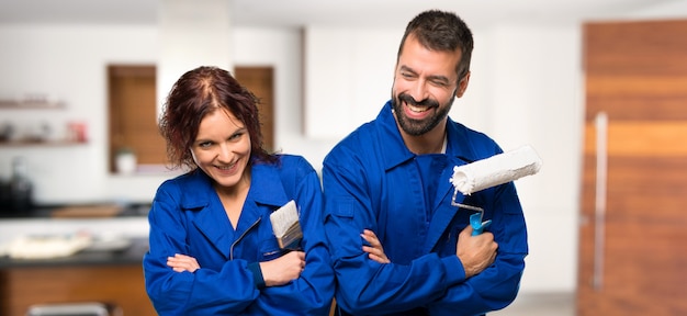 Pintores manteniendo los brazos cruzados mientras sonríen en casa.