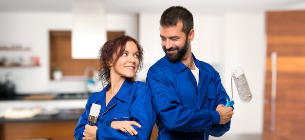 Pintores mirando por encima del hombro con una sonrisa en casa.