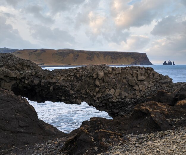 Pintoresca vista nocturna de otoño al océano de Reynisfjara playa de arena volcánica negra y formaciones rocosas desde Dyrholaey Cabo Vik Sur de Islandia Monte Reynisfjall en el fondo