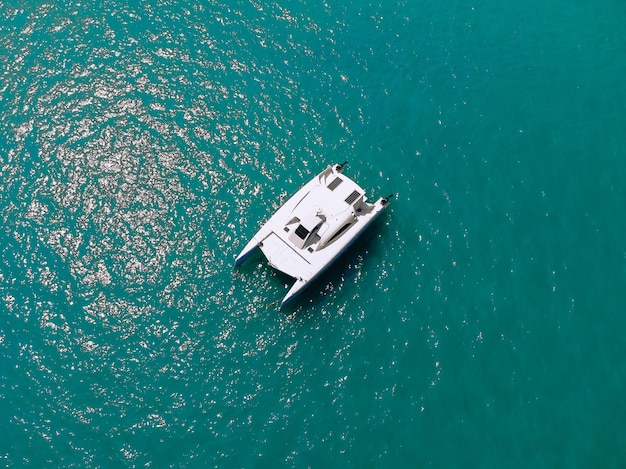 Pintoresca vista superior de un enorme catamarán blanco navegando por las profundidades del mar. Vista aérea.