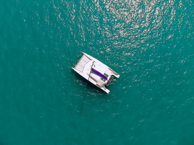 Pintoresca vista superior de un enorme catamarán blanco que navega por las profundidades del mar. Vista aérea.