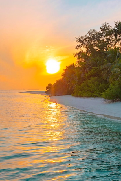 Pintoresco amanecer en la isla de Maldivas, el sol sale del océano Índico y se refleja en el concepto de viaje por agua