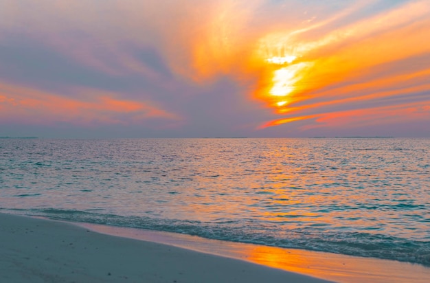 Pintoresco amanecer en la isla de Maldivas, el sol sale del océano Índico y se refleja en el concepto de viaje por agua
