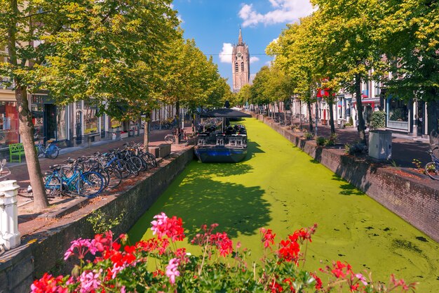 El pintoresco canal de Oude Delft y la torre inclinada de la iglesia protestante gótica de Oude Kerk en un día soleado en Delft, Holanda Meridional, Países Bajos.